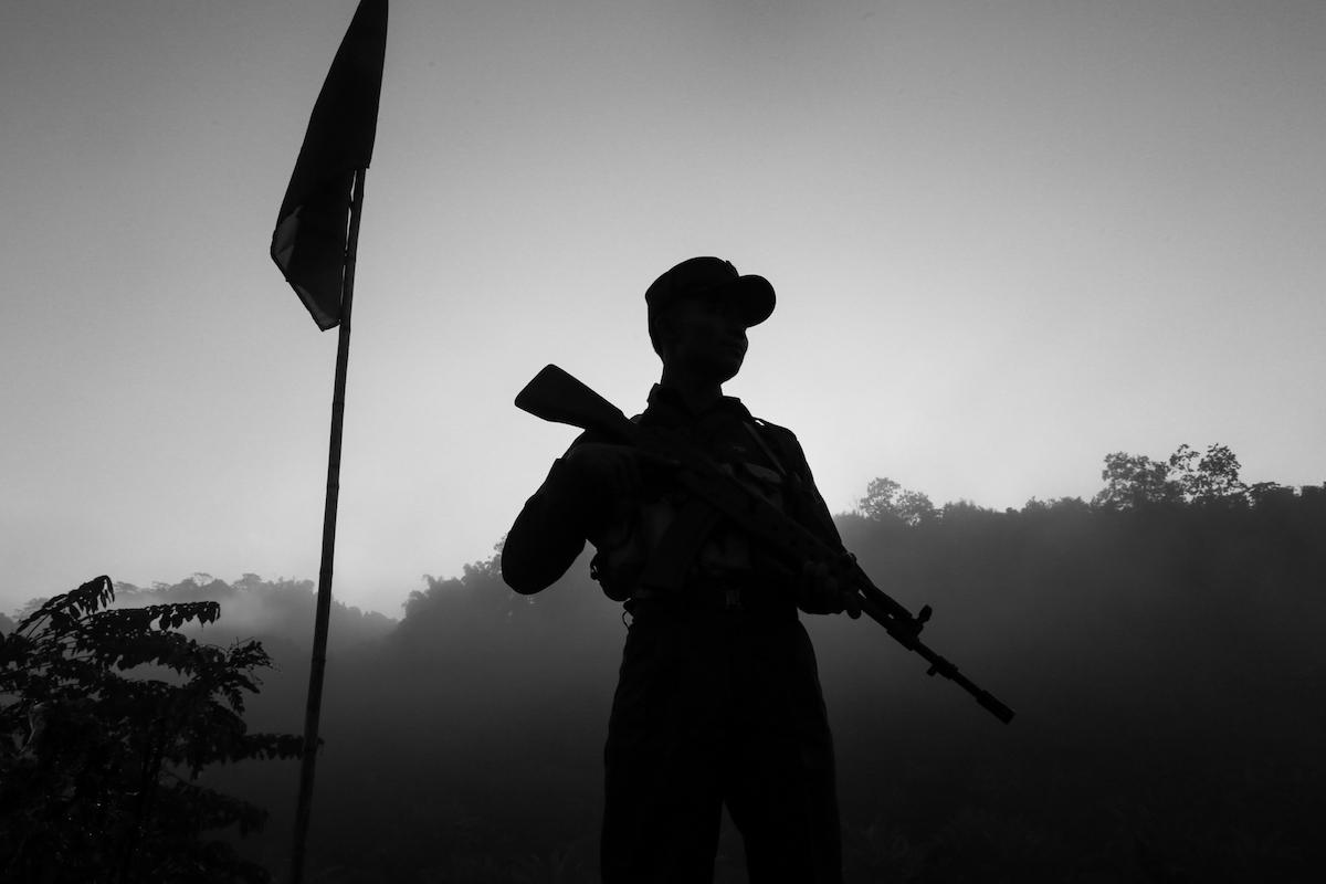 A soldier stands guard near a mountain as Myanmar military also deploy on the other side of the mountain.