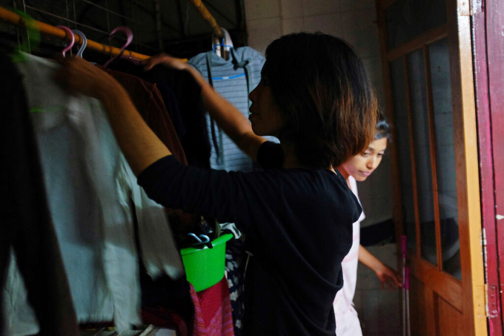 Pa Pa Phyo (foreground, Buddhist) and Thwe Thwe Oo (background, Christian) hanging cloths at the balcony.