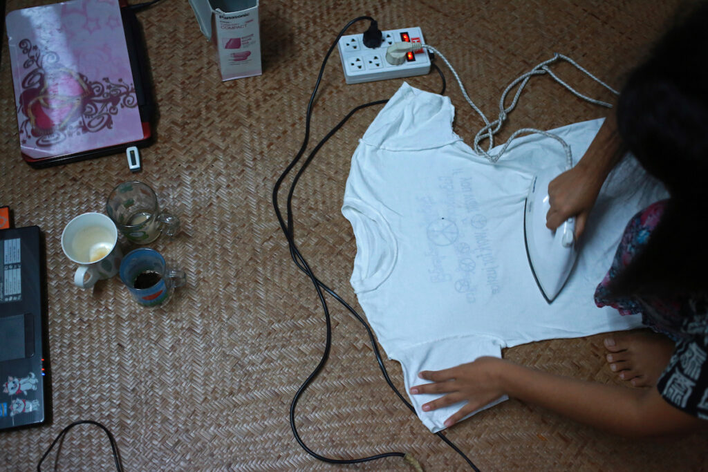 Khin Zar Mon (Muslim) ironing cloths in living room.