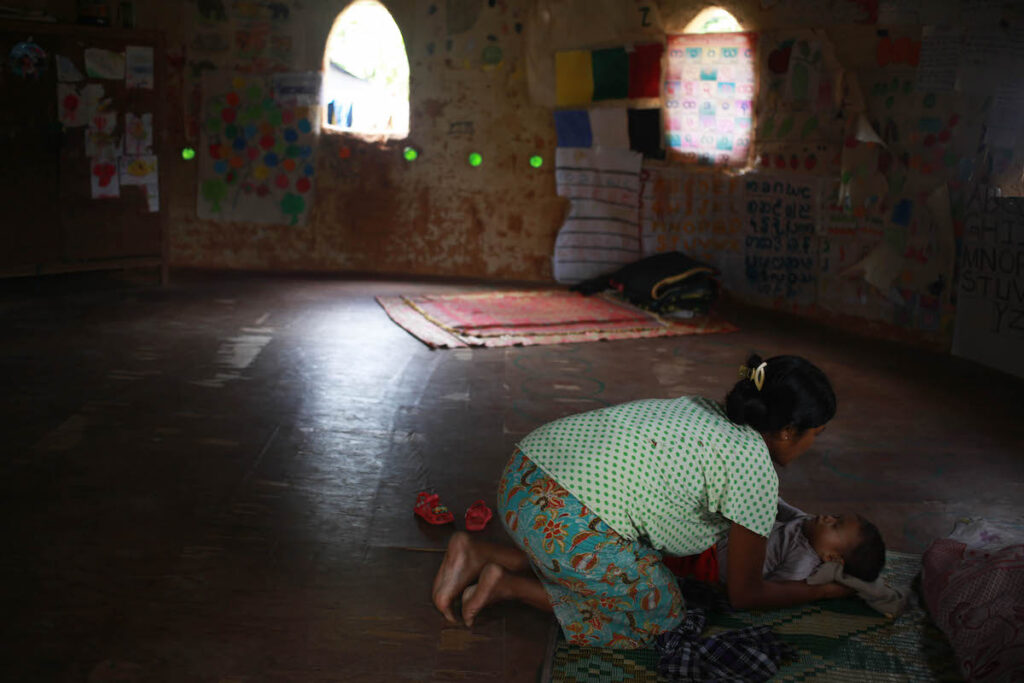 A mother comforts her baby inside a shalter in Je Yang IDP camp where over 8000 people living along side of the China-Myanmar border in Kachin State.